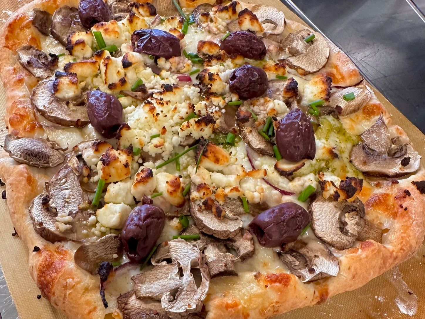 Bella mushroom pizzetta with roasted garlic, pesto, feta and olives