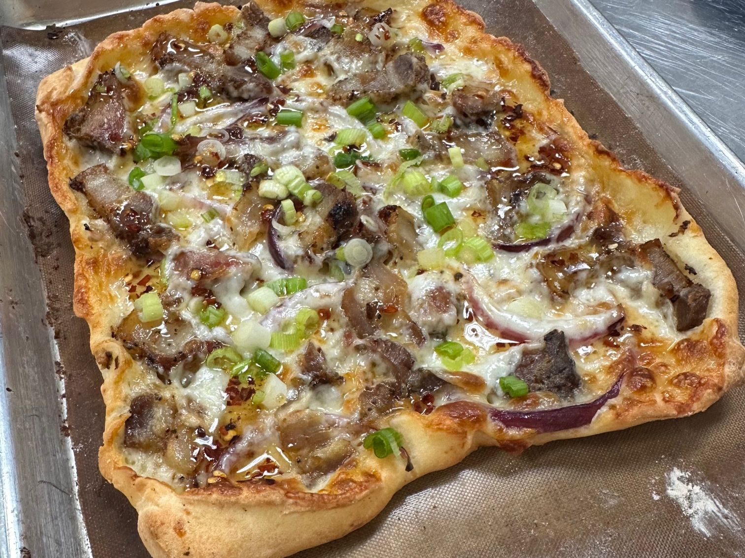 Pork belly pizzetta with red onions and spring onions